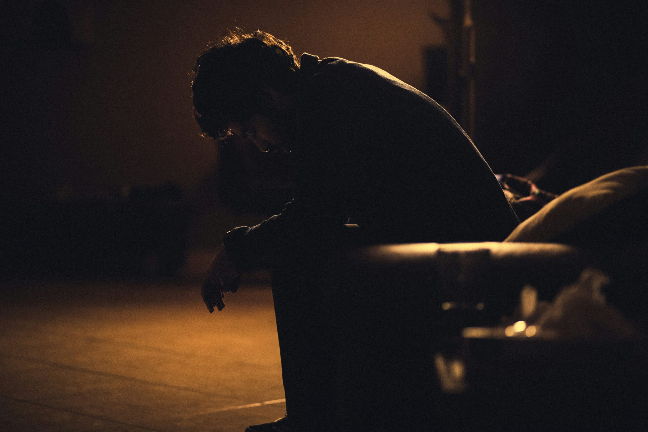 A man sitting slone, symbolising the mantra that boys don't cry